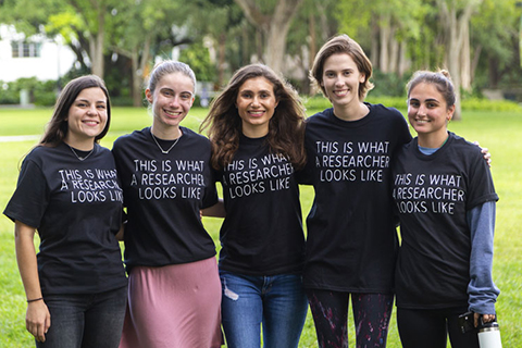 A group of women in shirts that say "This is what a researcher looks like" smile at the camera. 